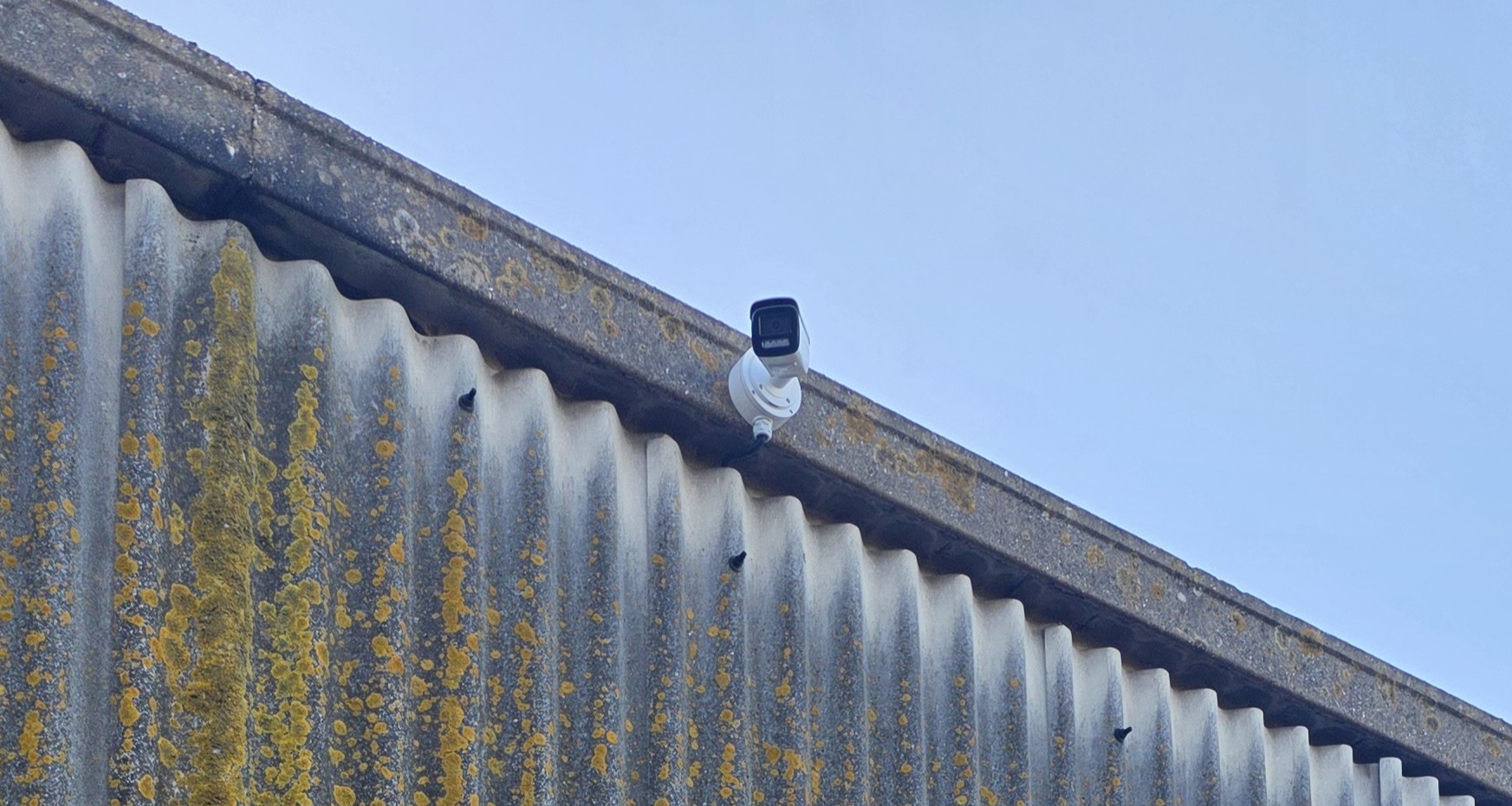 A weatherproof CCTV camera mounted high on the exterior of an industrial building to enhance site security.