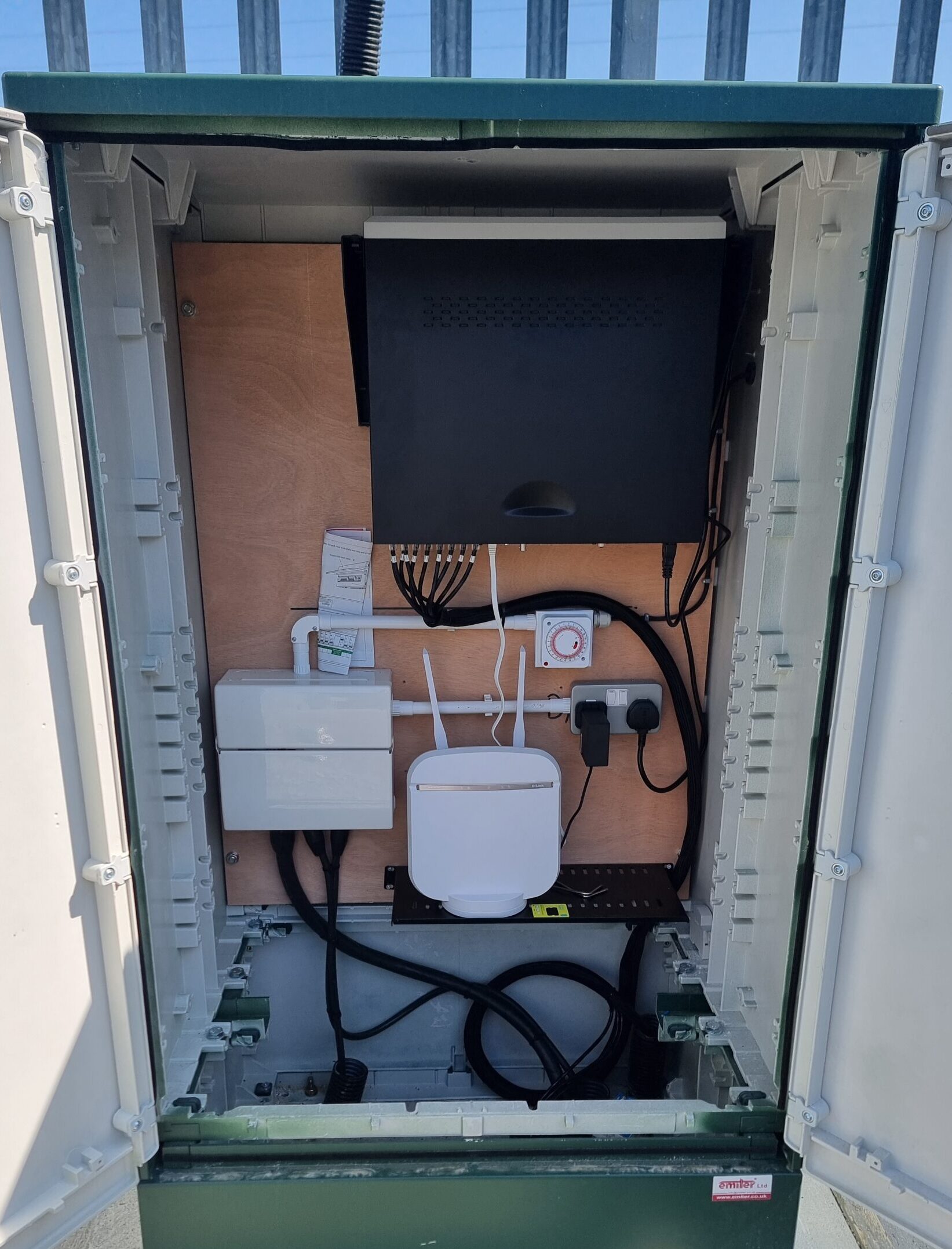 External weatherproof enclosure containing vertically mounted NVR, 5G router and network equipment at a commercial storage yard in Kent.