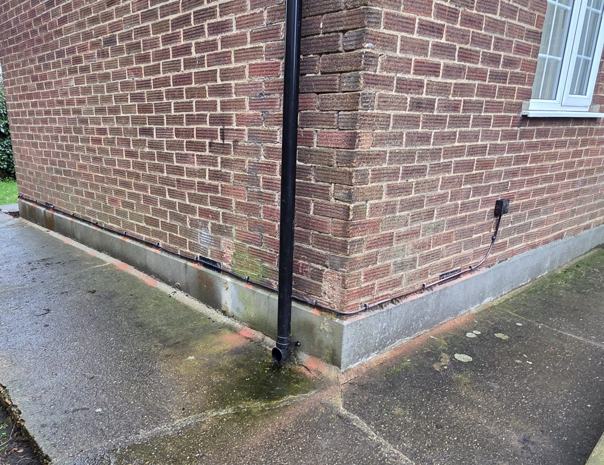 Cable neatly installed along the lower exterior wall of a brick building as part of an outdoor cabling route.