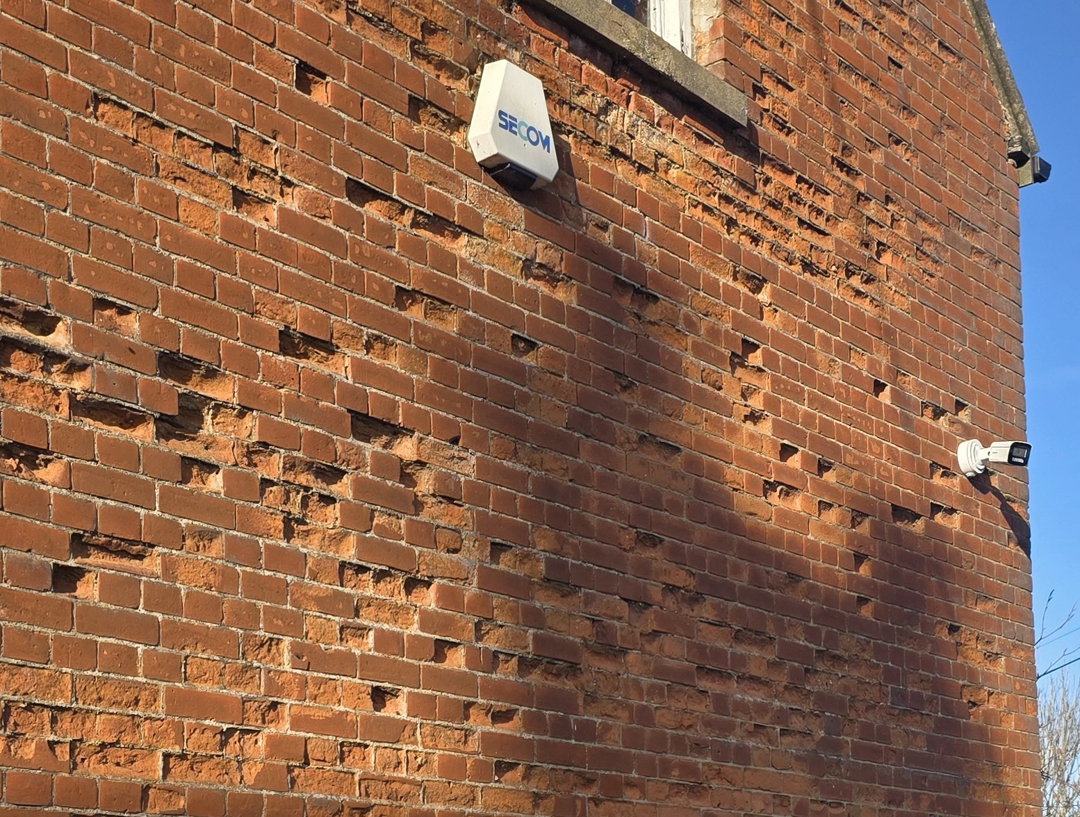 A CCTV camera mounted on the exterior brick wall of a building to provide outdoor security monitoring.