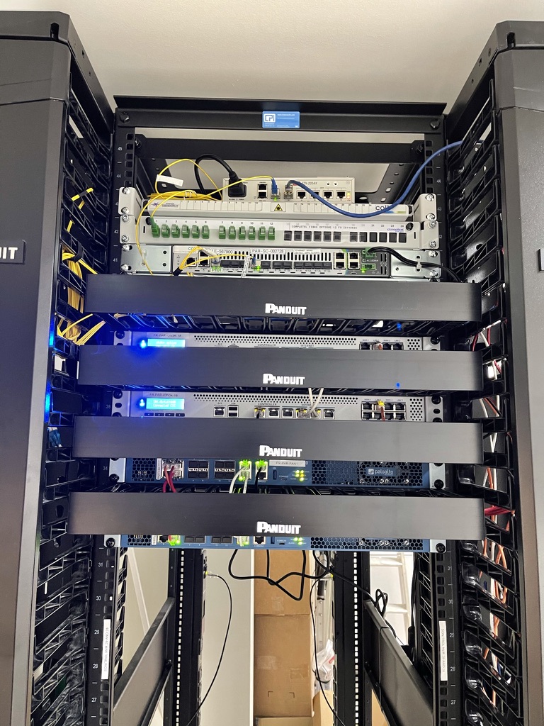 A fully equipped network rack containing fibre distribution hardware, patch panels, Panduit cable management, and rack-mounted network equipment.
