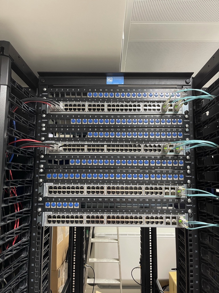 A commercial data cabinet containing multiple patch panels, network switches, and organised blue Cat6 cabling as part of a large‑scale network installation.