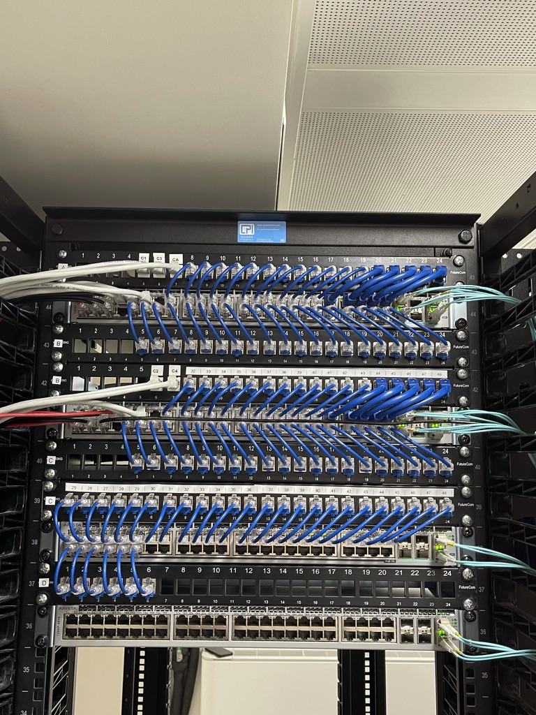 A neatly dressed high‑density data cabinet featuring multiple patch panels, blue Cat6 patch leads, fibre connections, and organised structured cabling.