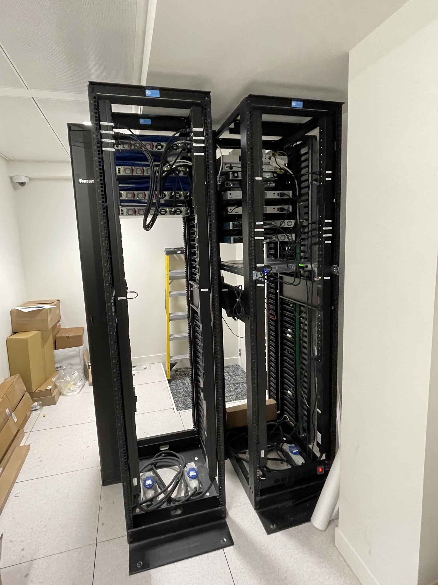 A partially completed network room containing several racks with patch panels, network switches, power distribution, and structured cabling in progress.