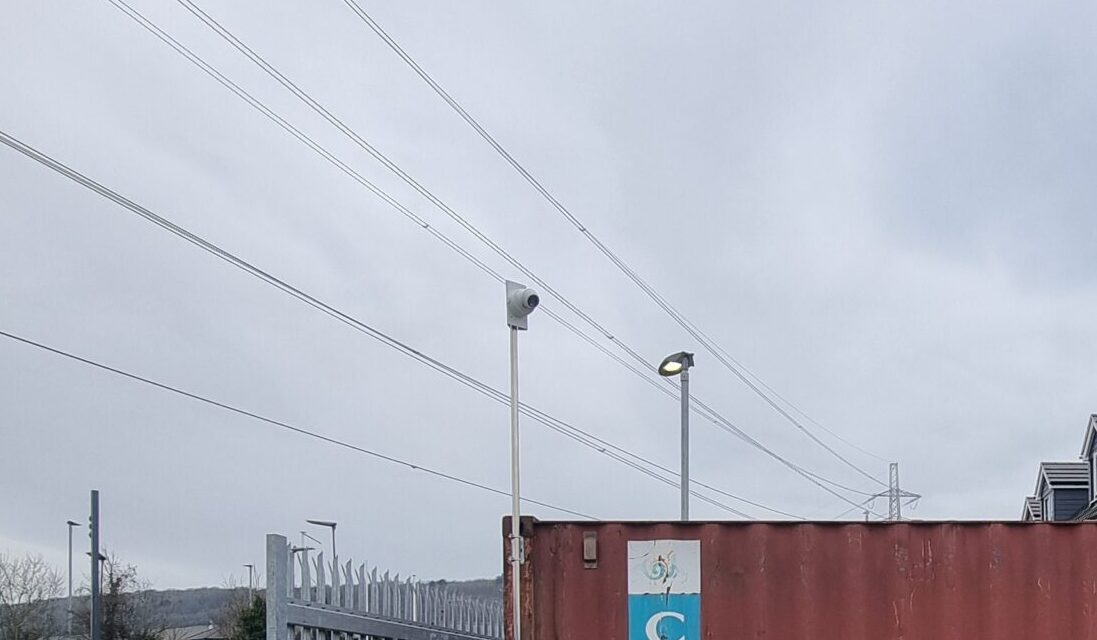 A CCTV camera mounted on a pole attached to a shipping container to provide perimeter monitoring and enhance site security.
